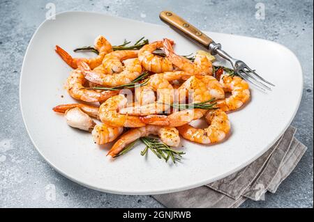 Crevettes frites crevettes crevettes dans une assiette avec herbes et ail. Arrière-plan gris. Vue de dessus Banque D'Images