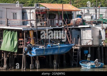 Un petit bateau avec moteur hors-bord suspendu d'un davit devant une maison de pilotis ('pang uk') sur le fleuve Tai O à Tai O, île Lantau, Hong Kong Banque D'Images