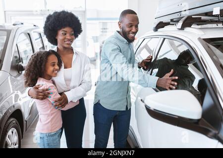 Une famille noire heureuse choisit une nouvelle voiture dans la salle d'exposition automobile. Concept de distribution locale du véhicule Banque D'Images