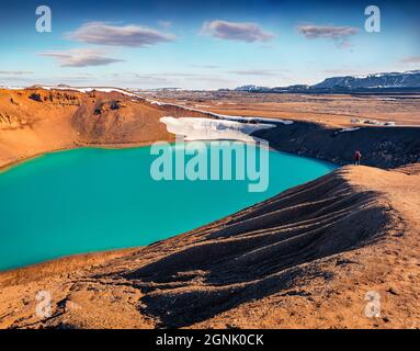 Tourisme debout sur le rivage de la falaise sur le lac Krafla Viti Crater. Scène estivale ensoleillée d'Islande, Europe. Concept de mode de vie de voyage. Antenne Banque D'Images