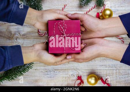 Les cadeaux du nouvel an entre les mains sur fond de bois. Mise au point sélective de Noël Banque D'Images