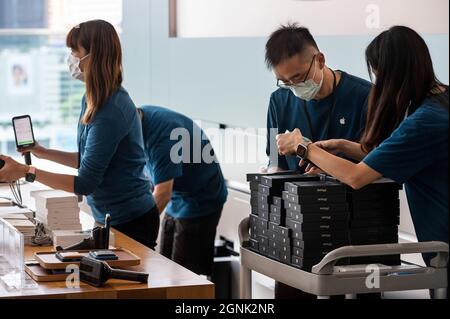 Hong Kong, Chine. 24 septembre 2021. Les employés d'Apple organisent des stocks de smartphones iphone 13 dans leur magasin tandis que les acheteurs font la queue pour entrer dans la file d'attente pendant le jour de lancement des nouveaux smartphones iPhone 13 à Hong Kong. Crédit : SOPA Images Limited/Alamy Live News Banque D'Images