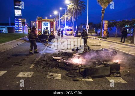 On voit des pompiers allumer un incendie dans la rue. Le festival traditionnel de la ville de Barcelone, la Merce, a posé les attractions une énorme foule de personnes buvant à la plage de Bogatell et au moment où la police a commis des émeutes d'expulsion ont éclaté avec la chute de bouteilles et la combustion de conteneurs. Banque D'Images