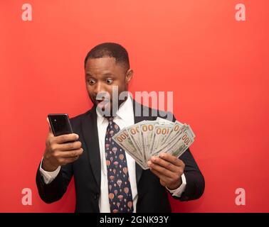 homme regarde dans le téléphone, homme tenant des billets de dollar dans sa main Banque D'Images