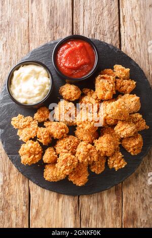 Pop-corn à base de poulet américain avec deux sauces en gros plan sur une table en ardoise. Vue verticale du dessus Banque D'Images