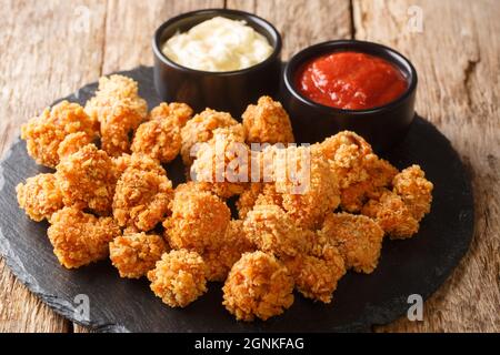 Portion de collation maison maïs soufflé au poulet avec deux sauces gros plan sur un tableau d'ardoise sur la table. Horizontal Banque D'Images