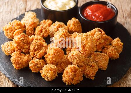 Croustillant de poulet Popcorn avec ketchup à la tomate et mayonnaise en gros plan dans le plat d'ardoise sur la table. Horizontale Banque D'Images