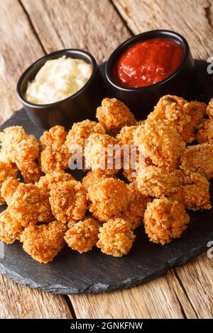 Le poulet au popcorn est un plat composé de petits morceaux de poulet qui ont été panés et frits en gros plan dans le plat d'ardoise sur la table. Ven Banque D'Images