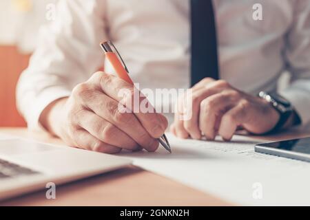 Homme d'affaires écrivant des notes à la réception, gros plan avec une attention sélective Banque D'Images