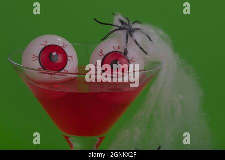 Gros plan d'un cocktail sanglant avec des globes oculaires sur fond vert. Concept Halloween minimal. Banque D'Images