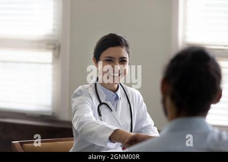 Heureux succès jeune médecin indien donnant poignée de main au patient Banque D'Images