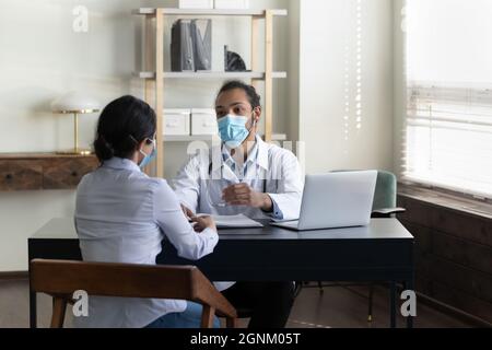 Jeune homme de race mixte médecin en facemask rencontre avec le patient Banque D'Images