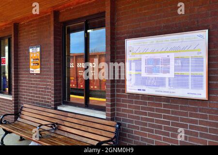 Bensenville, Illinois, États-Unis. Un train de marchandises qui passe se reflète dans la fenêtre d'une gare de banlieue. Banque D'Images