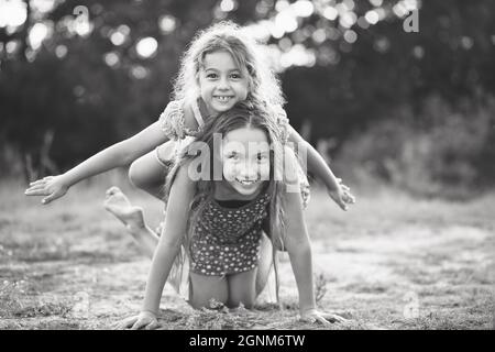 Portrait noir et blanc de deux jolies petites filles jouant et riant à la campagne. Concept de plein air pour les enfants heureux Banque D'Images