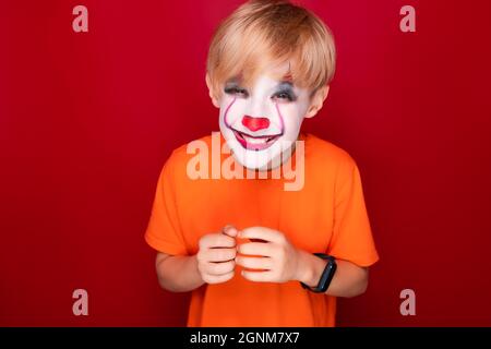 sly garçon avec maquillage pour les fêtes de sourires d'halloween, se déchine les yeux. Banque D'Images