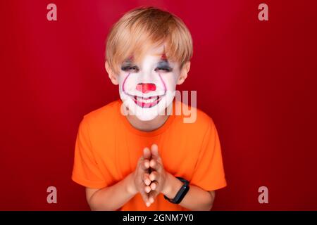 sly garçon avec maquillage pour les fêtes de sourires d'halloween, se déchine les yeux. Banque D'Images