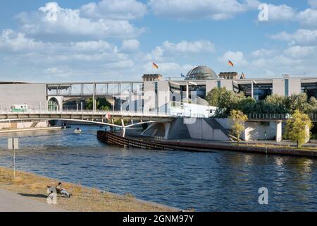 Berlin, Allemagne - 20 juillet 2013 : homme solitaire assis au banc près de la rivière Spree en bas de Berlin avec vue sur les édifices modernes du Parlement et le Reichstag Banque D'Images