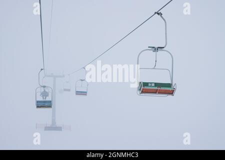 Les téléphériques pendent les câbles dans un brouillard silencieux Banque D'Images