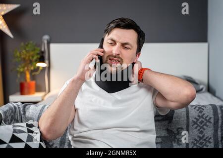 Homme dans la mousse col cervical appelle au téléphone à la compagnie d'assurance pour l'assistance médicale après accident, sensation de douleur de cou, de blessures et Banque D'Images