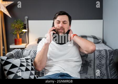 Homme dans la mousse col cervical appelle au téléphone à la compagnie d'assurance pour l'assistance médicale après accident, sensation de douleur de cou, de blessures et Banque D'Images