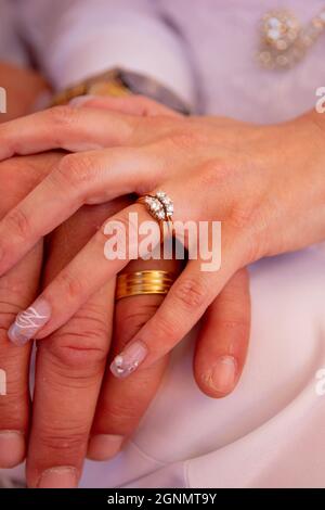 Gros plan d'un couple marié tenant les mains avec des anneaux de mariage sur les doigts Banque D'Images