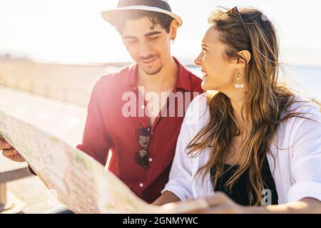 Jeunes enfants couple de voyageurs lisant la carte à la plage en vacances Banque D'Images