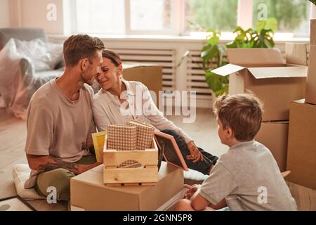 Portrait de famille heureuse avec son déballer des boîtes dans la pièce confortable tout en se déplaçant dans la nouvelle maison, l'espace de copie Banque D'Images