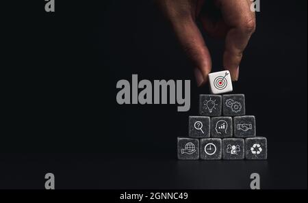 Stratégie d'entreprise avec processus de réussite de croissance pour le concept de leadership et de travail d'équipe. Main mettant l'icône de cible d'affaires sur le cube dés blocs de la pyramide de pile Banque D'Images