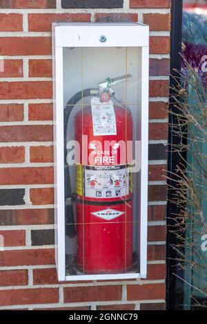 Un extincteur d'incendie Amerex rouge dans une armoire sur un mur de briques extérieur. Banque D'Images