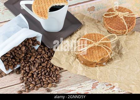Stroopwafels empilés sur du papier brun, à côté des haricots et de la tasse de café. Banque D'Images