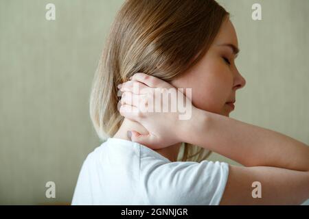 La femme tient le cou avec douleur spasme du muscle cervical à la main. Douleurs au cou, vertèbres cervicales, maladie du système musculo-squelettique chez la jeune femme Banque D'Images