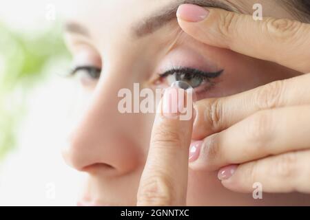 Une jeune femme met des lentilles de contact souples sur un gros plan des yeux Banque D'Images