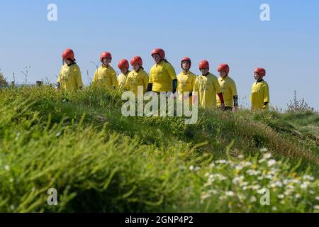 Des adolescents portant de l'équipement de sécurité et marchant le long du chemin de la côte pour commencer une aventure de codirection à Towan Head à Newquay, dans les Cornouailles. Banque D'Images