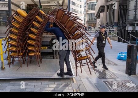 Les entrepreneurs du fournisseur de meubles d'accueil « Well Tadred tables » chargent de grandes piles de chaises d'événement dans la société camion après une réception à Lloyds of London dans la City of London, le quartier financier de la capitale, le 24 septembre 2021, à Londres, en Angleterre. Banque D'Images