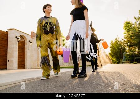 Des enfants blancs souriant tout en faisant des trucs ou des friandises pendant l'Halloween en plein air Banque D'Images