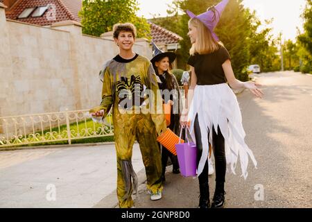 Des enfants blancs souriant tout en faisant des trucs ou des friandises pendant l'Halloween en plein air Banque D'Images