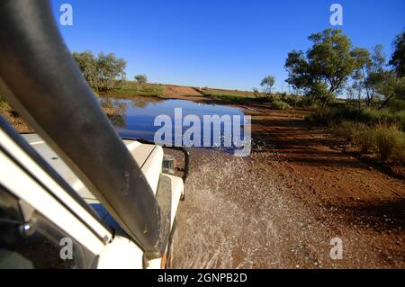 Jeep conduite à travers une flaque d'eau sur une route non pavée, Australie, Oodnadatta Banque D'Images