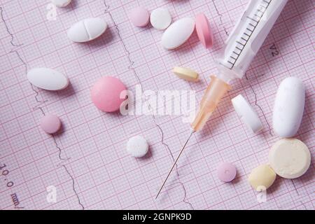 stéthoscope, pilule médicale et seringue sur un diagramme cardio. Banque D'Images