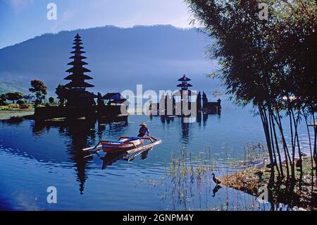 Indonésie. Bali. Temple au bord du lac Bratan. Homme en canoë. Banque D'Images