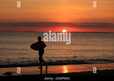 Gower, Swansea, Royaume-Uni. 24 août 2021. Météo au Royaume-Uni: Un garçon aime arnaqueter les hilades sous un soleil couchant, lors d'une soirée sèche, fine et ensoleillée à la plage de Llangennith sur la péninsule de Gower. Les perspectives pour les prochains jours sont pour le même beau temps avec quelques sorts chauds.Credit: Gareth Llewelyn/Alamy Banque D'Images