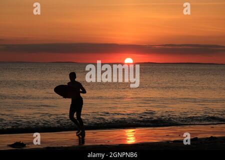 Gower, Swansea, Royaume-Uni. 24 août 2021. Météo au Royaume-Uni: Un garçon aime arnaqueter les hilades sous un soleil couchant, lors d'une soirée sèche, fine et ensoleillée à la plage de Llangennith sur la péninsule de Gower. Les perspectives pour les prochains jours sont pour le même beau temps avec quelques sorts chauds.Credit: Gareth Llewelyn/Alamy Banque D'Images