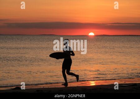 Gower, Swansea, Royaume-Uni. 24 août 2021. Météo au Royaume-Uni: Un garçon aime arnaqueter les hilades sous un soleil couchant, lors d'une soirée sèche, fine et ensoleillée à la plage de Llangennith sur la péninsule de Gower. Les perspectives pour les prochains jours sont pour le même beau temps avec quelques sorts chauds.Credit: Gareth Llewelyn/Alamy Banque D'Images