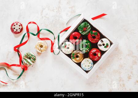 Beignets colorés dans une boîte cadeau et à côté. Des beignets de Noël avec glaçage au sucre en cadeau. Vue de dessus, espace vide Banque D'Images
