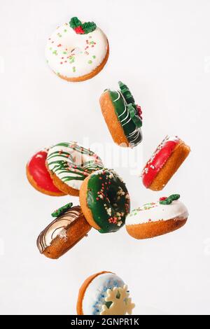 Beignets de Noël volant. Beignets colorés avec des arrosettes tombant ou volant en mouvement sur fond blanc. Mise au point sélective Banque D'Images