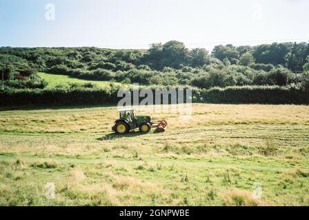Tracteur coupant de l'herbe dans les champs de ferme Bolberry en direction de Hope Cove, Kingsbridge, Devon, Angleterre, Royaume-Uni. Banque D'Images