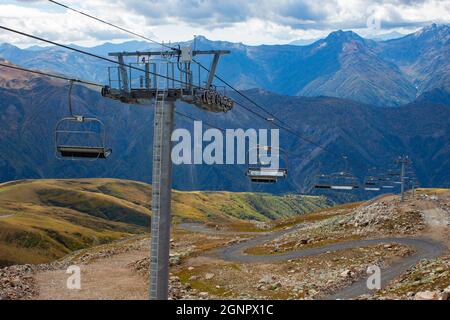 Téléphérique avec sièges ouverts dans les montagnes en été. Remontée mécanique dans le Caucase en Géorgie. Vue depuis le sommet de la montagne. Banque D'Images