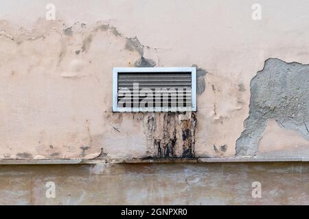 Grille de ventilation extérieure sale et graisseux avec des stries de saleté sur un vieux mur de restaurant en ciment pelé. Grille du système de climatisation non propre pour technique Banque D'Images