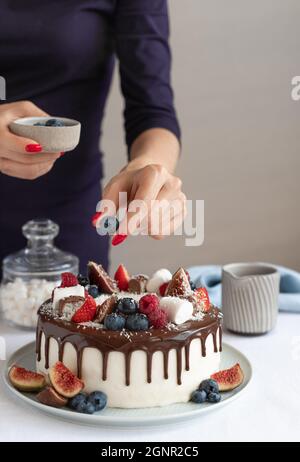 Confiseur décorant le gâteau blanc avec des baies fraîches Banque D'Images
