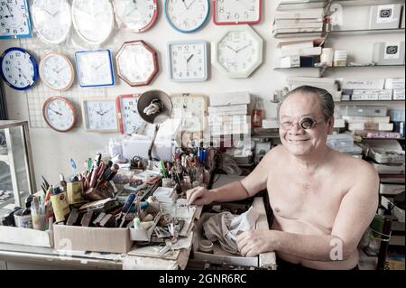 Phang Nga, Thailand - FEBRUARY 1, 2016: Portrait of an Asian elder watchmaker with eyeglass loupe working in his watch shop. Thai Mueang. Banque D'Images
