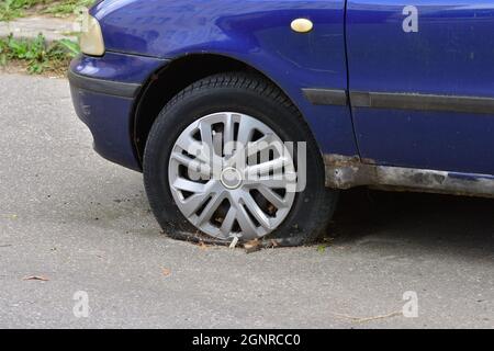 La voiture endommagée se trouve sur des pneus à plat dans le parking. Mettre au rebut. Banque D'Images